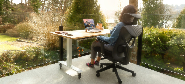 a woman working on her computer on a balcony in a modern house