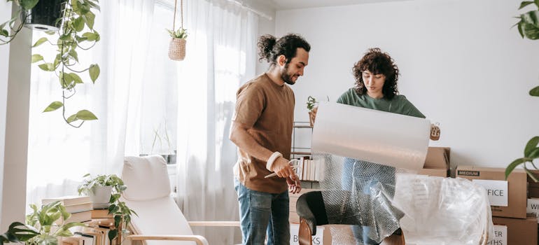 two people wrapping their furniture in protective material