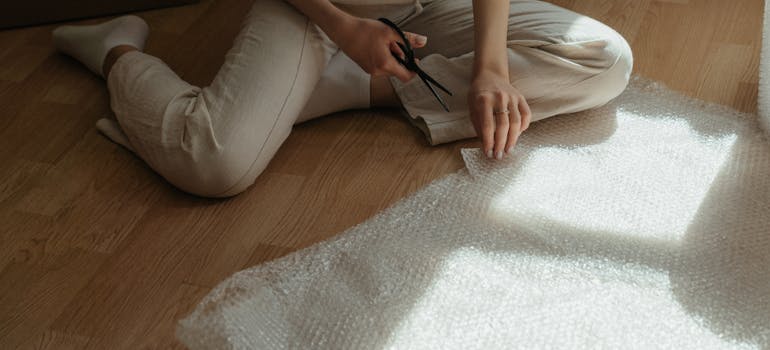 a woman cutting a bubble pack she intends to use to safely move fragile items