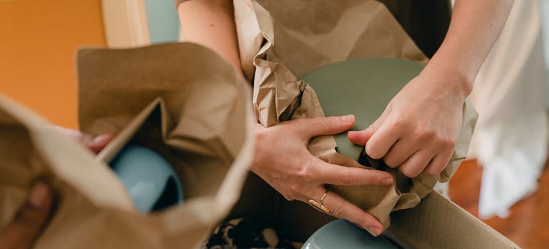 two people wrapping some items made of ceramic