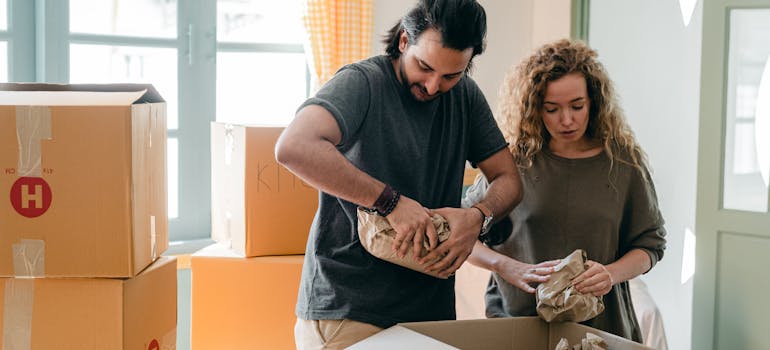 two people making sure there is no space in a box