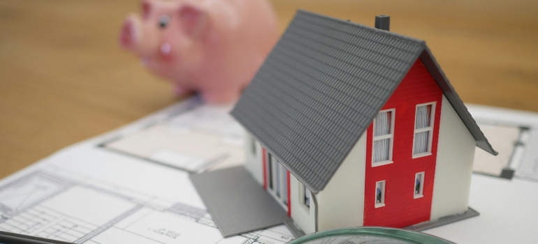 a model of a house and a piggy bank representing one of the common misconceptions about living in Washington DC