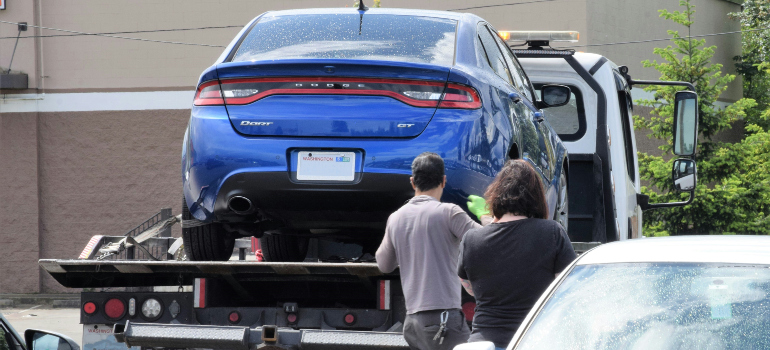 a blue car being carried by a tow truck