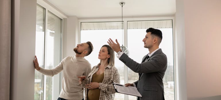 a man and a pregnant woman are viewing an interesting house together with the owner