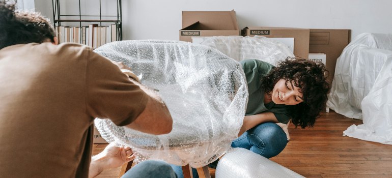 couple wrapping a chair in bubble wrap