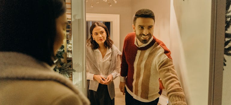 two people opening their door to a guest