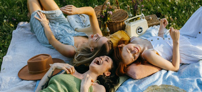 four ladies having a picnic in the park and looking very amused