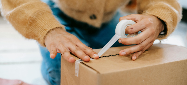 woman sealing a box with tape