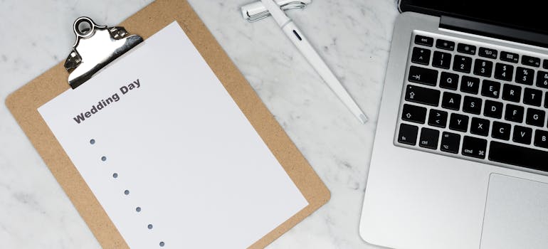 laptop, pen, and clipboard on a white desk