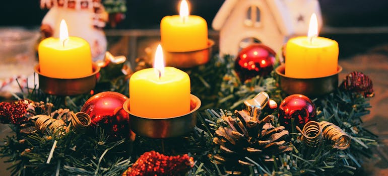 four Christmas candles next to a white porcelain house