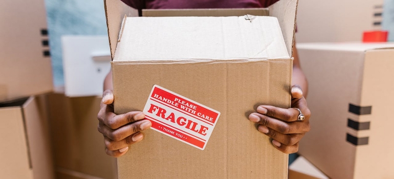 A man holding a labeled cardboard box.