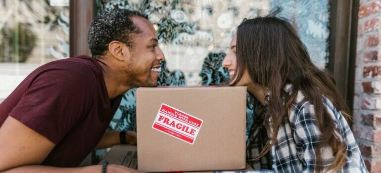 a couple holding boxes while waiting for movers Prince William County offers 