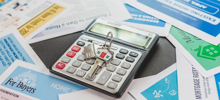 a calculator and a house key on top of it, amid a pile of papers