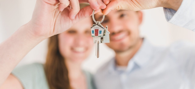 The happy couple is holding and showing a house key after moving with movers Fredericksburg VA has to offer. 