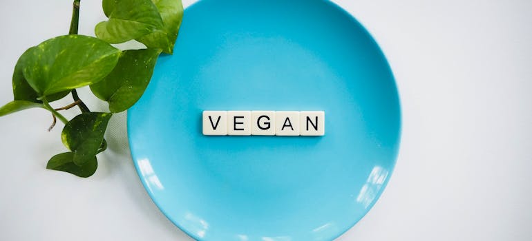 a blue plate with the word "vegan" spelled with Scrabble tiles