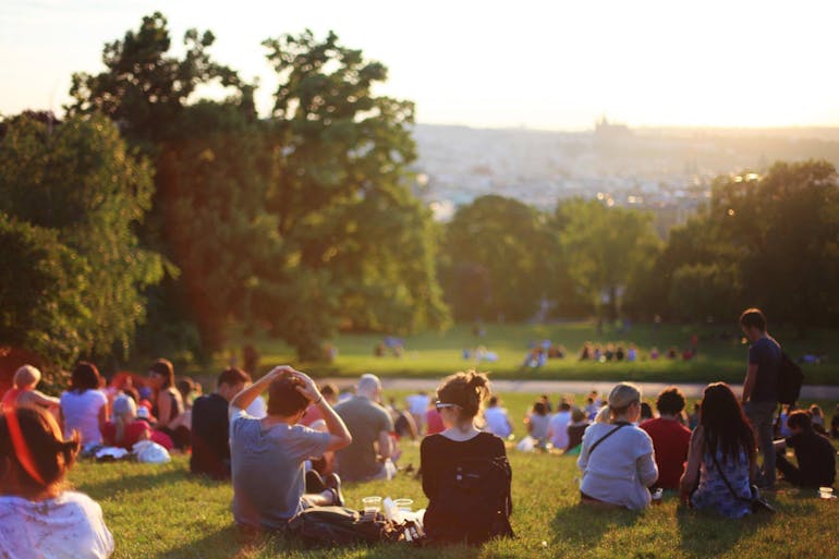 People sitting on the grass and talking about suburbs for families moving to Virginia