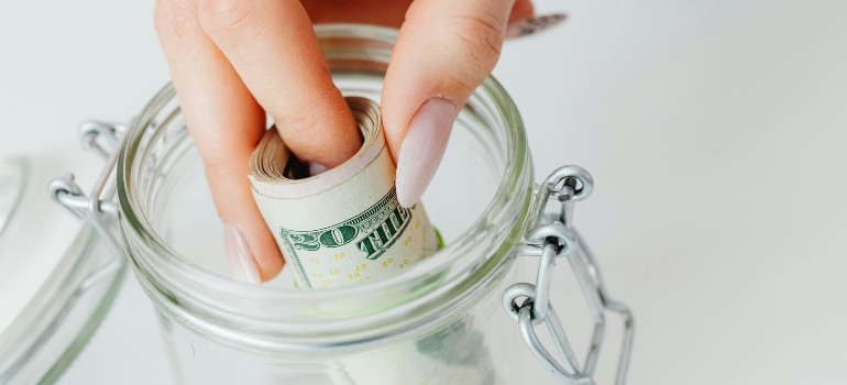 Close-Up Shot of a Person Saving Money in the Glass Jar
