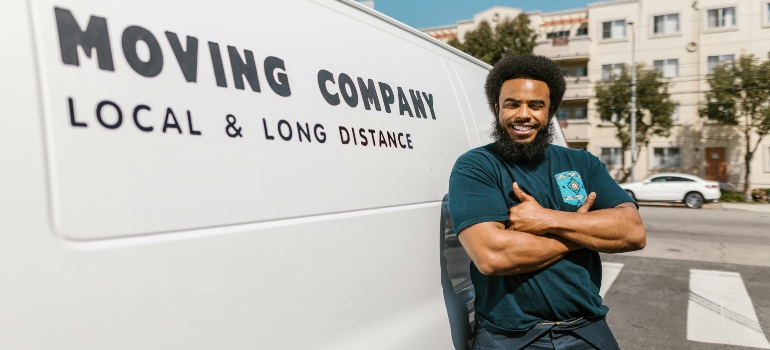 Man in Blue T-shirt and Black Pants Standing Beside White Van