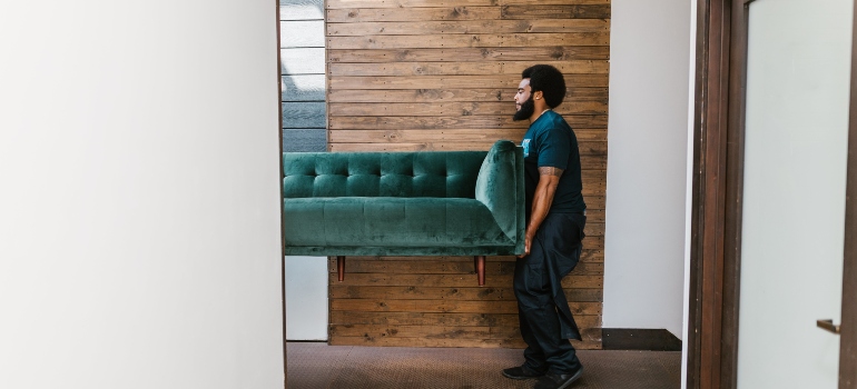 Man in Blue Denim Jeans Sitting on Green Sofa helping to decommission an office space in Virginia.
