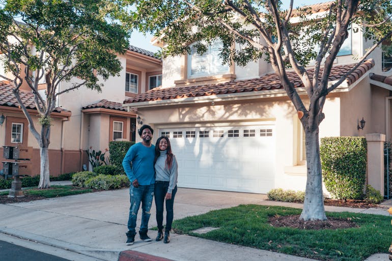 Couple standing in front of a house and thinking about moving from Manassas to Bowie