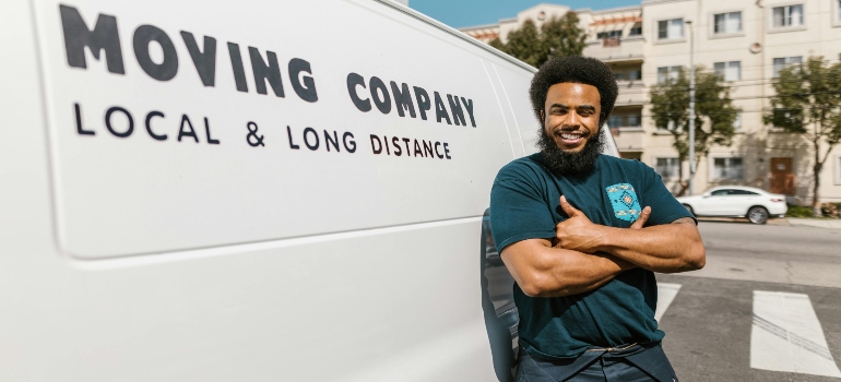 Man in Blue T-shirt and Black Pants Standing Beside White Van trying to spare time and energy when moving.