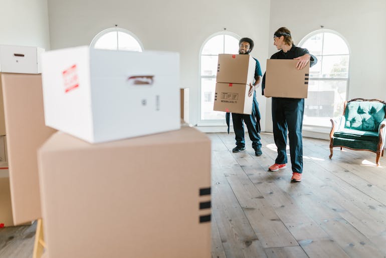 Two men holding boxes and thinking about lifting and moving heavy objects safely