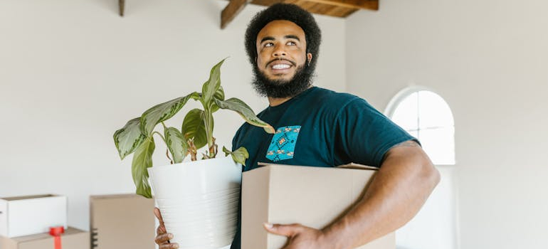 a mover holding a box and a flower pot