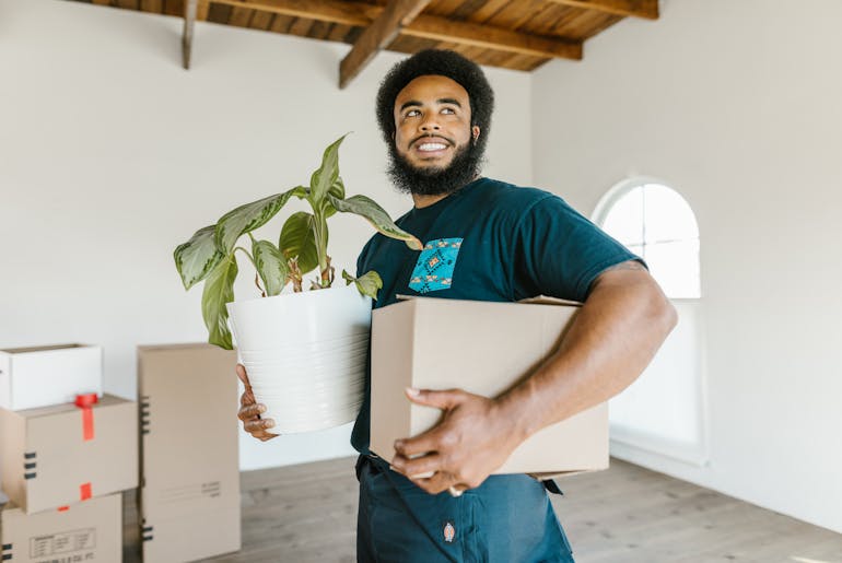 Man holding a plant and a box