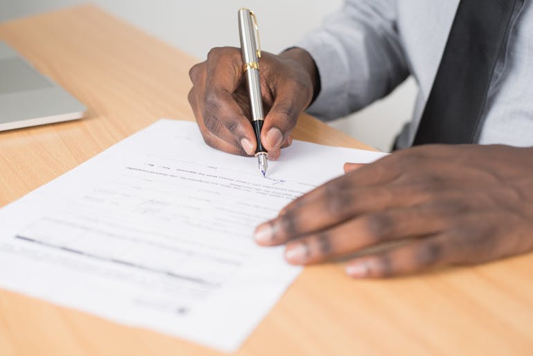 Person holding a pen and writing on the paper 