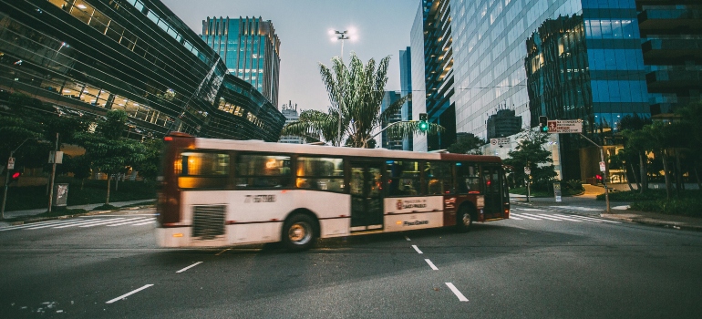 White Bus on Road Near in High Rise Building during Daytime