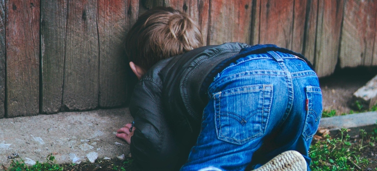 Photo of Boy Peeking on Brown Wooden Fence