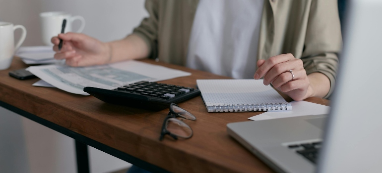 Woman sitting on a desk trying to do legal and administrative tasks to handle before moving to a new state.