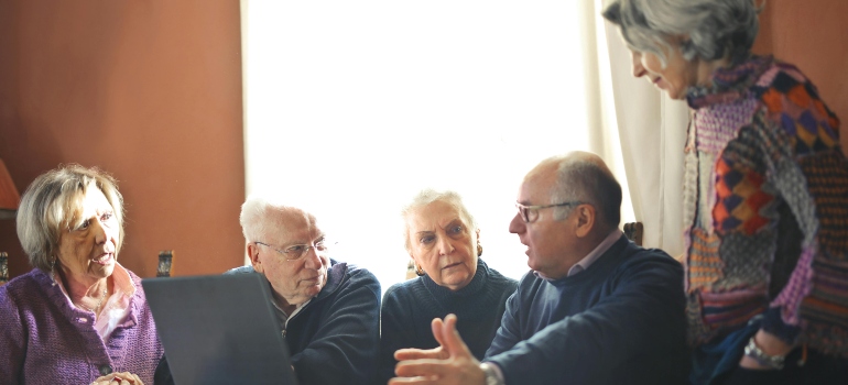 Elderly People Sitting at Table talking about whether hiring movers is a must.