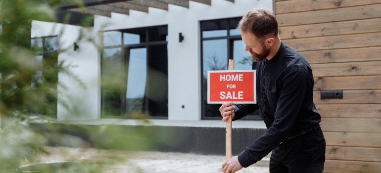 Person putting up a sign in front of a house