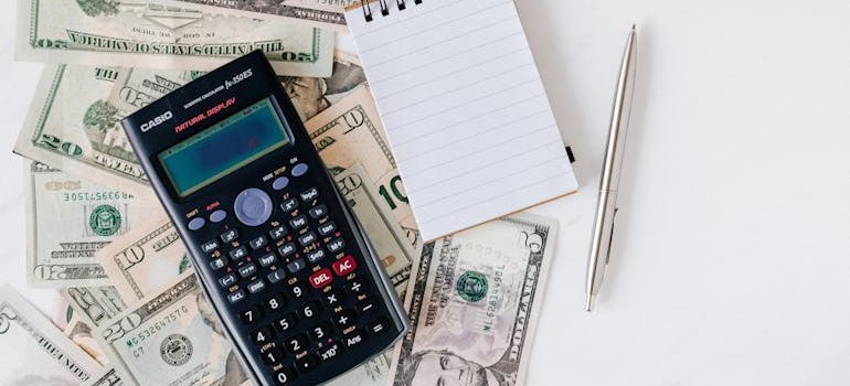 a calculator and a notebook on a pile of cash