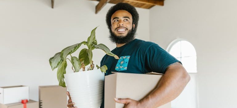 a mover holding a box and a flowerpot