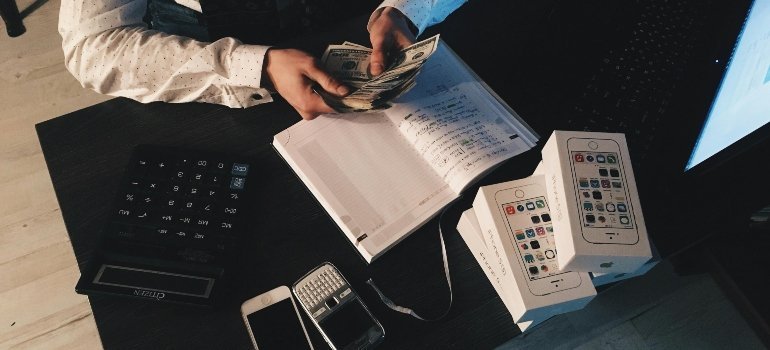 Man calculating moving expenses and counting cash for a Maryland moving quote.