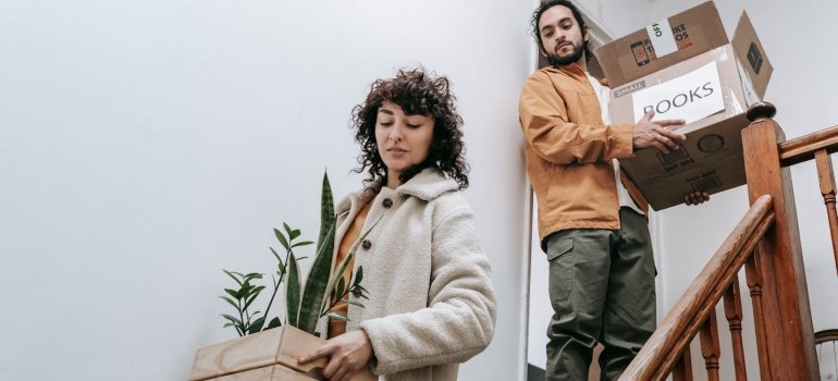 Couple carrying boxes down the stairs