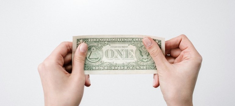 Hands holding a single dollar bill—emphasizing cost-conscious, high-value living available in this region.