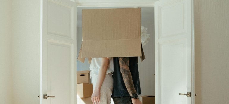 Two people standing back-to-back with a box covering their heads, turning moving day into a fun memory.