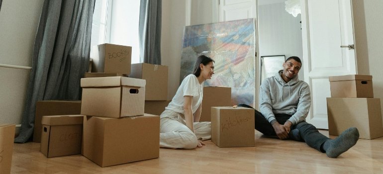 Smiling couple surrounded by moving boxes, beginning to unpack in their new home.