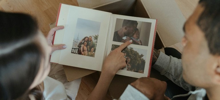 Two people reminisce over a photo album, reflecting on memories from their move from Alexandria to Manassas.