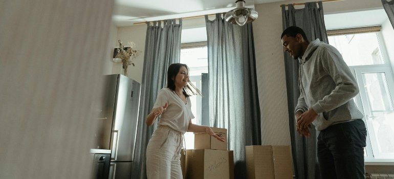 A cheerful couple unpacking boxes together in their new home’s kitchen area, radiating excitement.