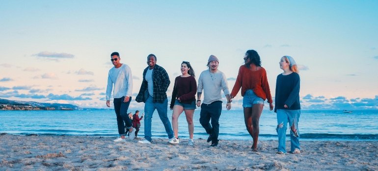 A diverse group of friends walking and laughing along a sunny beach, capturing the relaxed lifestyle found while living in Prince William County.