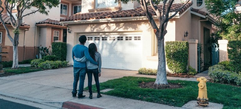 A couple embraces while gazing at the front of their new home, representing a fresh chapter.
