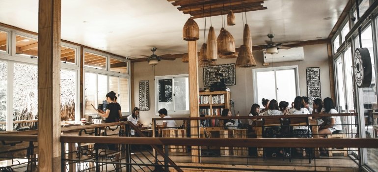 People chatting inside a modern, warmly lit café with wooden furniture and cozy ambiance.