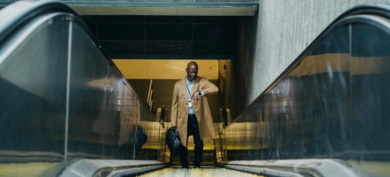 A professionally dressed man checks his watch while descending an escalator—highlighting the pace of life for professionals living in Prince William County.