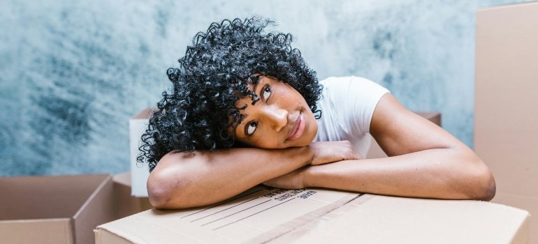 A woman rests her head on moving boxes while planning her move from Washington to Alexandria.