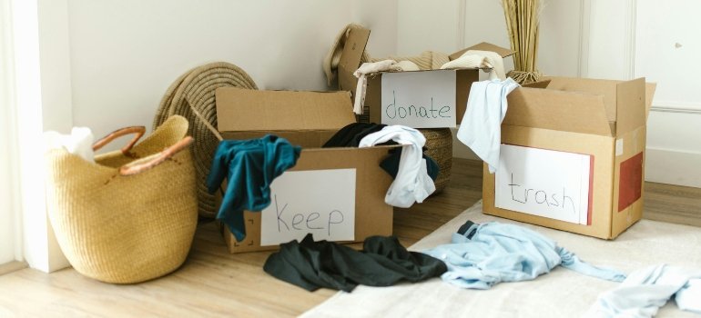 Labeled boxes filled with clothes for keeping, donating, and trashing — part of moving from Baltimore to another Maryland city.