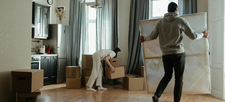 Two people organizing boxes and carefully moving artwork into their new home.